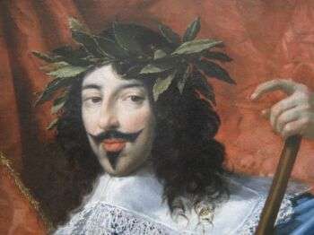 Painting of Louis XIII of France. He wears a plant-crown, is in a white outfit, has pale skin and dark hair. Moreover, he is standing in front of a red background. 