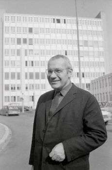 Max Bill - artiste suisse (1908-1994) Photographie en noir et blanc devant un grand bâtiment.
