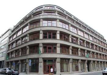 Immeuble de bureaux à Breslau : Un grand immeuble d'angle avec des accents métalliques rouges le long des fenêtres.