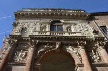 Palazzo del Capitaniato photo de bas en haut. Il ya une seule arche qui se trouve au milieu, la moitié inférieure est d’une couleur rose rouille tandis que le haut est bronzé. Il y a divers ornements qui composent la structure. 