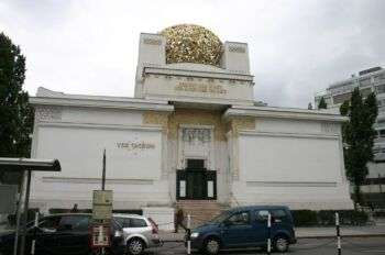 Palácio de Exposições da Secessão de Viena: um grande edifício branco com uma esfera dourada no topo e vários pormenores dourados. 