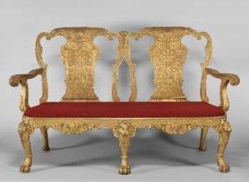 Gilded gesso on walnut; previously covered in eighteenth-century red silk damask not original. A golden two-person chair with a red cushion, which was likely designed by Benjamin Goodison.