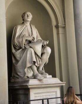 Sculpture de Filippo Brunelleschi dans une pierre claire avec lui regardant vers le haut avec un crayon et du matériel d'écriture dans ses mains.