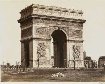 Arc de Triomphe de l'Ètoile taken in an old black and white photo. The structure consists of a single arch that sits in Paris, France. 