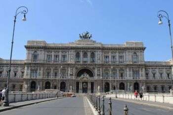 Palace of Justice, Rome, which is a large light stone building with numerous arched windows and three distinct floors. 