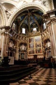 Catedral de Valencia: el interior de una grande estructura en forma de cúpula, decorada con pinturas religiosas, varias flores doradas y decoraciones renacentistas. 