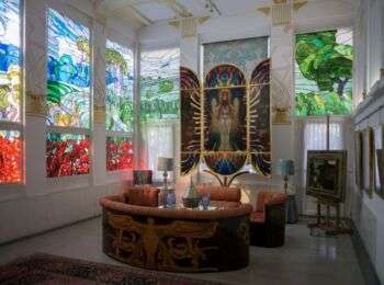 Interior of Villa Wagner with elaborate stain glass windows and colorful imagery of nature. 
