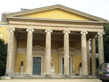 A large yellow building with six columns along the front. Further, it is located in West Wycombe Park house in Buckinghamshire.
