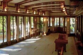 Sala da pranzo della casa Robie di Frank Lloyd Wright: foto d'interni del suo progetto. Ampia sala con travi in legno lungo il soffitto e una pianta ampia e aperta. 