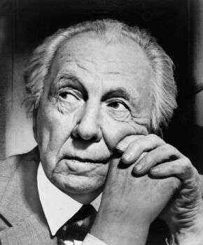 Frank Lloyd Wright photo: Black and white picture of the man looking to the left with his head resting on his hands. 