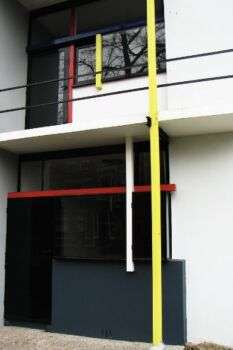 Maison Rietveld-Schroder (1924) en trecht : Une structure blanche simple avec des accents jaunes et rouges sous la forme de fines lignes rectangulaires attachées à la structure.